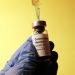 Covid Vaccine bottle with a syringe inserted into it being held by a hand in surgical glove by Hakan Nural Unsplash - 360onhistory.com