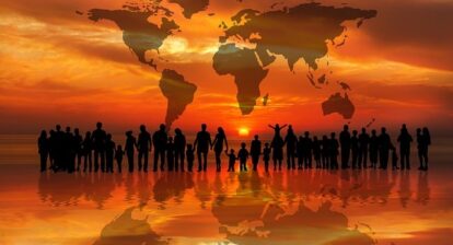 Shadows of people both adults and children standing in front of a sunset with a projection of a world map in the background. Population Gerd Altamann Pixabay