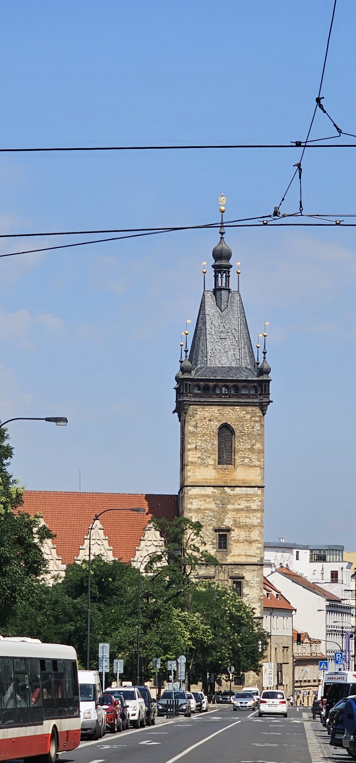 The New Town Hall in Prague, where the first Defenestration took place in 1419. A tower with two windows can be seen across road. In front of the town hall are some trees.