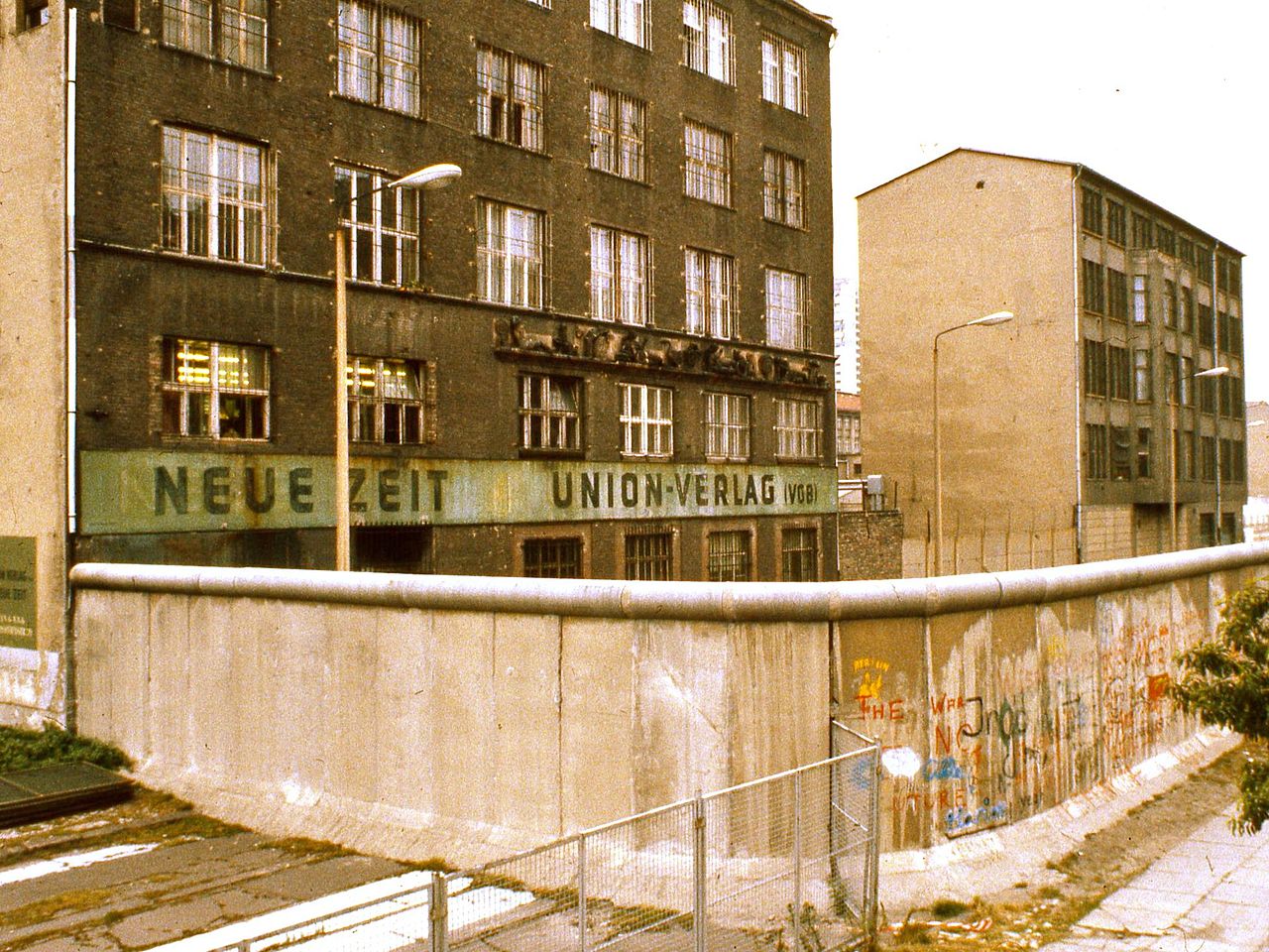 Exterior of East Berlin Neue Zeit newspaper building (from the rear), with Berlin Wall in foreground, 1984. Other information Photo by George Garrigues.