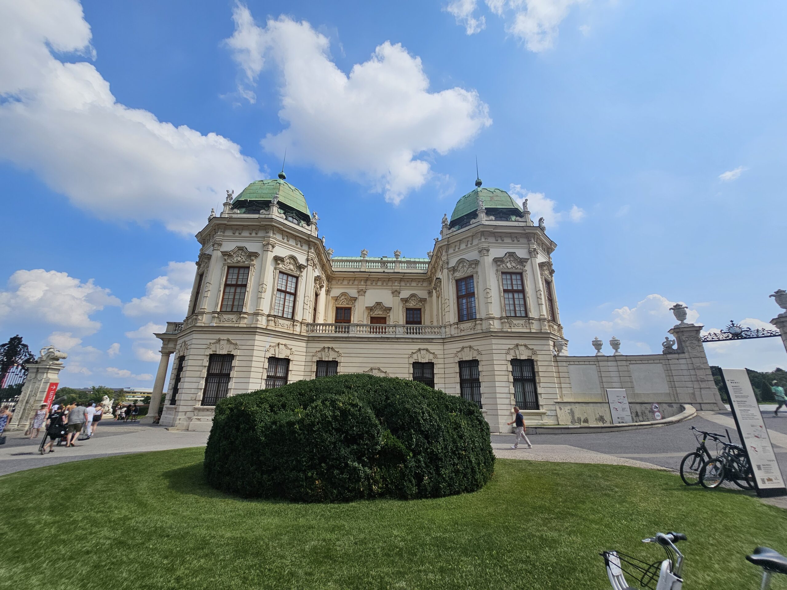 Sideview of Upper Belvedere Palace, with two domes and a lawn in front.