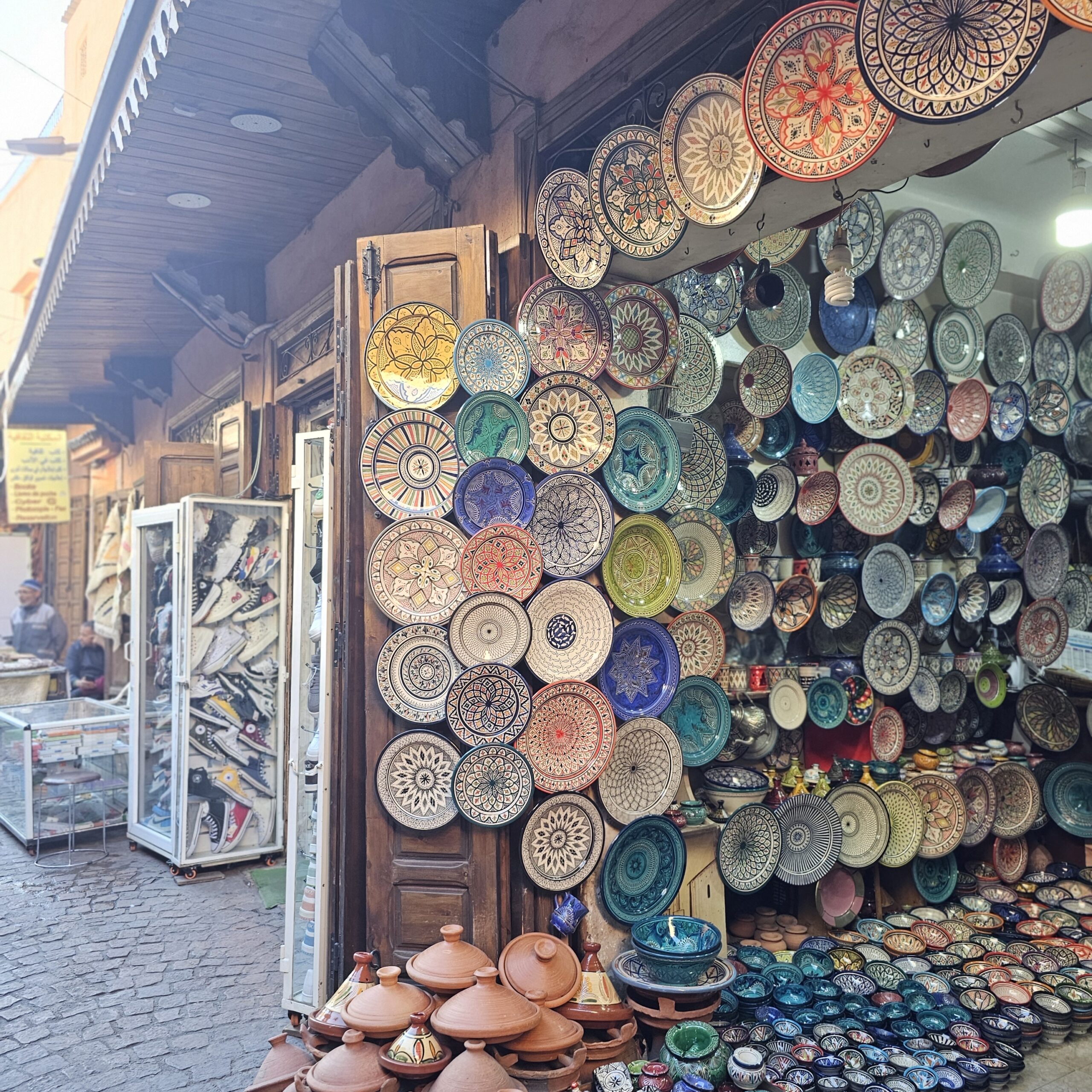 A stall selling colourful Moroccan plates and dishes in a souk in Jemaa El Fnaa, Marrakesh. Image by 360onhistory.com