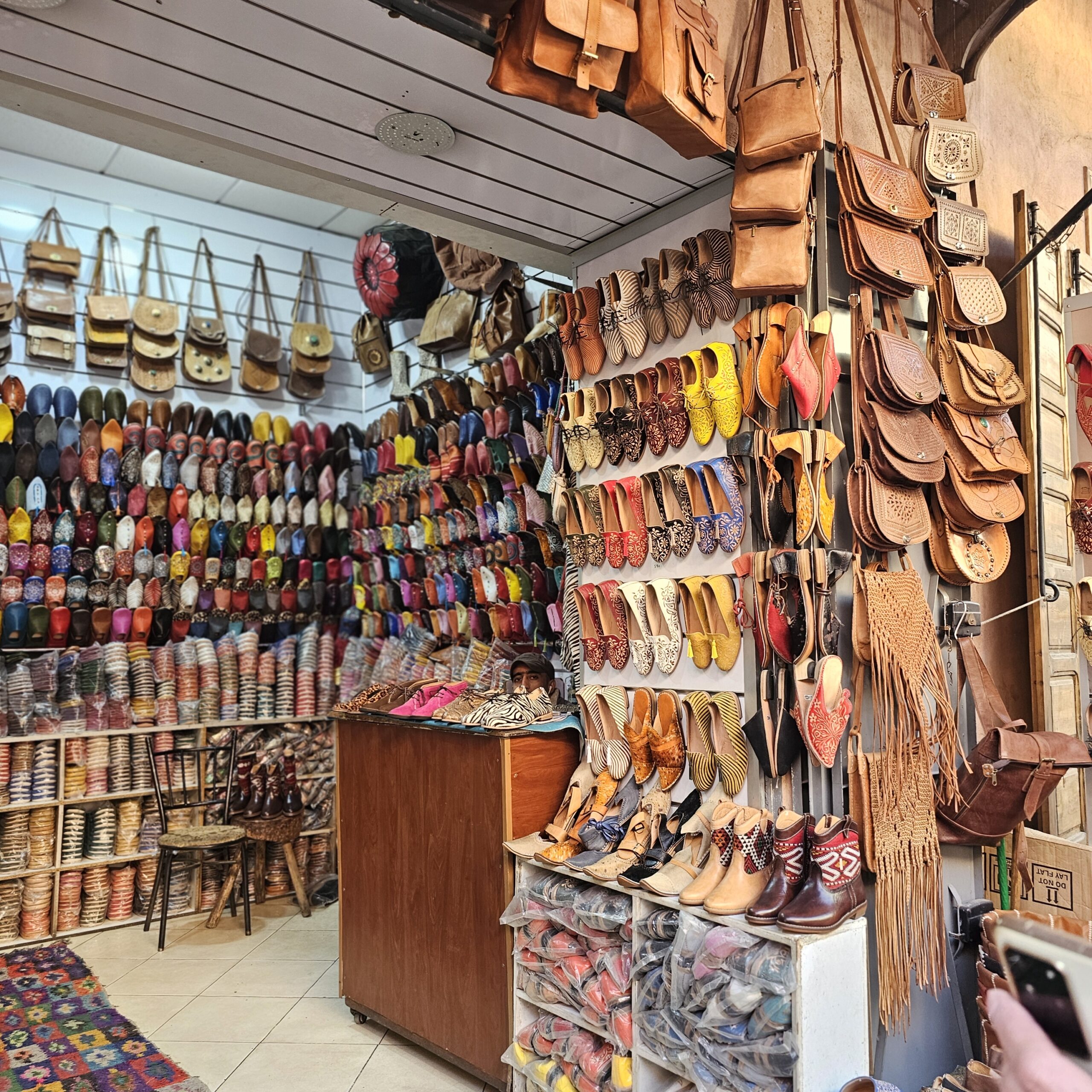 A stall selling Moroccan leather bags and shoes in a souk in Jemaa El Fnaa, Marrakesh. Image by 360onhistory.com