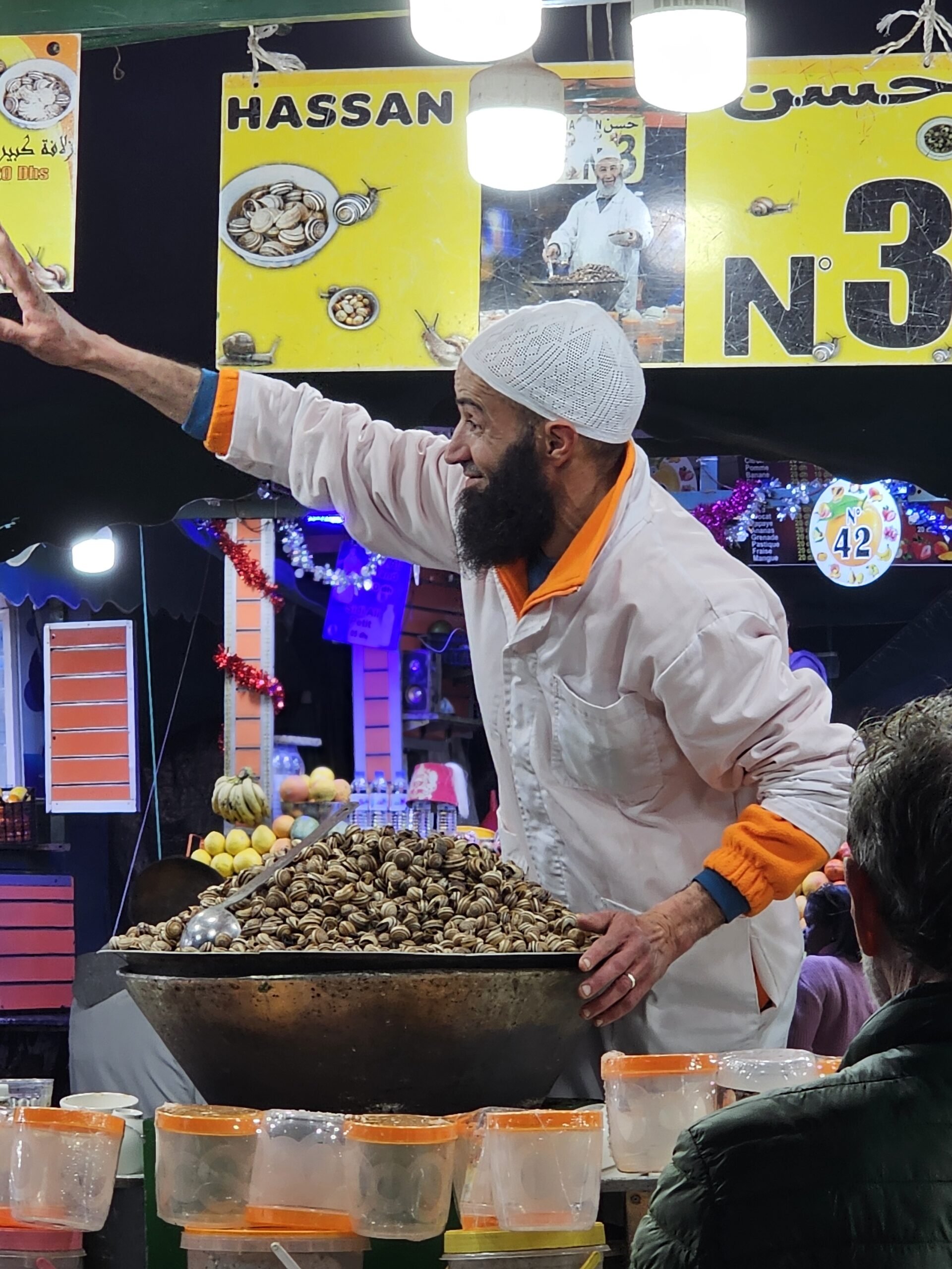 A man in white chef's coat and hat selling local delicacy, snail soup, at Jemaa el Fnaa, Marrakesh. Image by 360onhistory.com