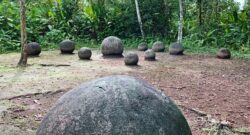 Costa Rican Stone Spheres by Diego Padilla Duran and Mariordo in a field. There are about 9 spheres one of them in close up while 8 can be seen further up.